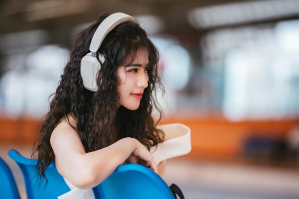 A beautiful woman is singing a song wearing headphones, seeing somewhere. 