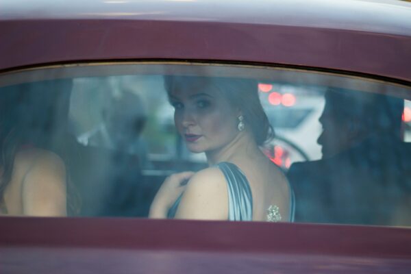 The woman seated inside the car and trying to see something outside.