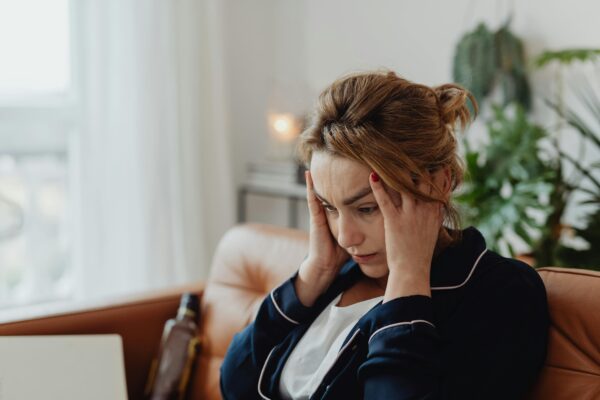 A woman is seated putting her hands on her head, denoting cognitive dissonance and dark psychology facts.